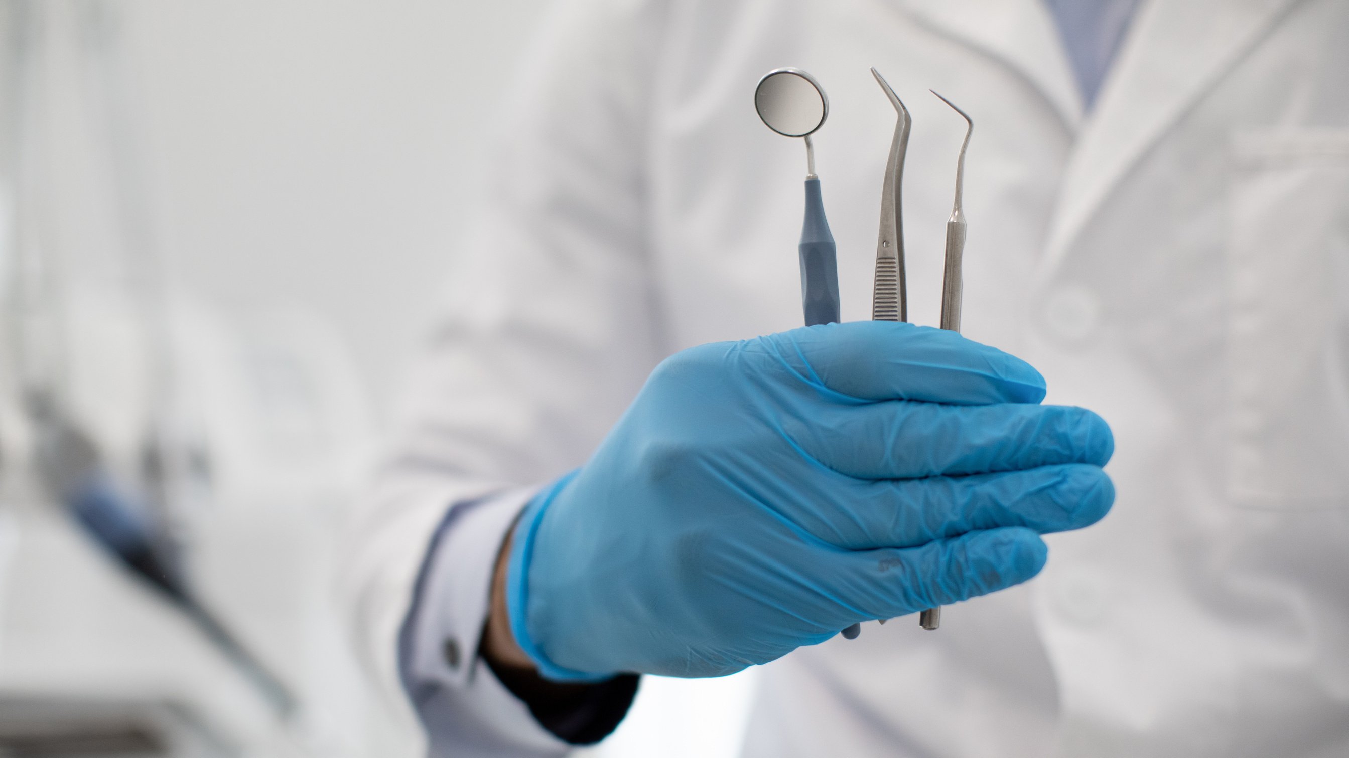 Unrecognizable Dentist Doctor in Blue Sterile Glove Holding Dental Tools in Hand